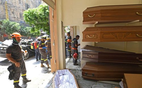 Lebanese and French rescuers gather near a damaged funeral services shop in Beirut, on August 6, 202