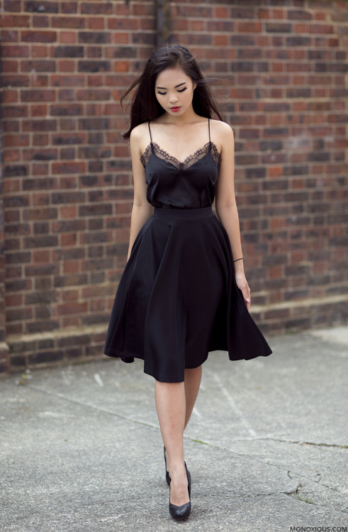 Arissa is wearing a lace detail black dress underneath a full skirted black skirt, teamed with simpl