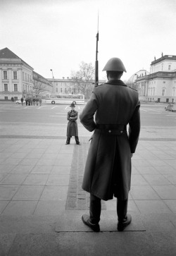 theunderestimator-2: David Bowie in stunning attire, facing a guard in the communist -at the time- East Berlin, Germany, on April 1976, in a photo by   Andrew Kent. This feels like the moment before the shootout scene from a post-modern western movie.