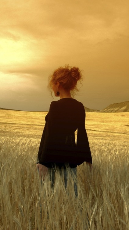 Farm girl overdressed in a field of wheat.