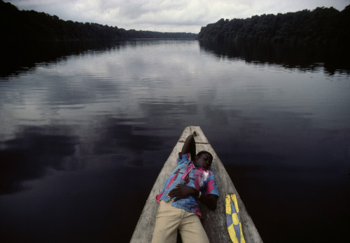 ouilavie:Bruno Barbey. Gabon. 1984. A young man rests on a boat cruising up the Ogooue River.