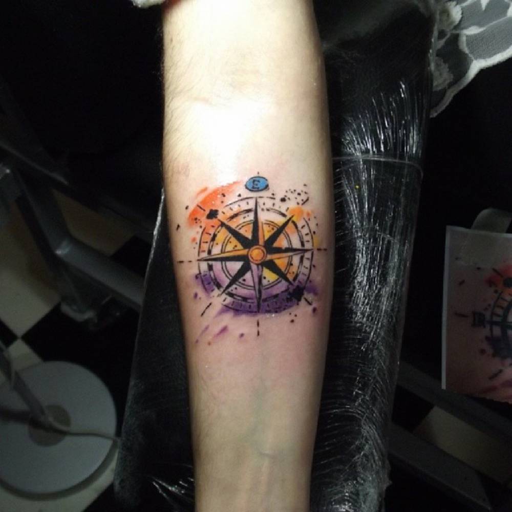 pequenostatuajes:  Tatuaje de una brújula con fondo de acuarela. Artista tatuador: