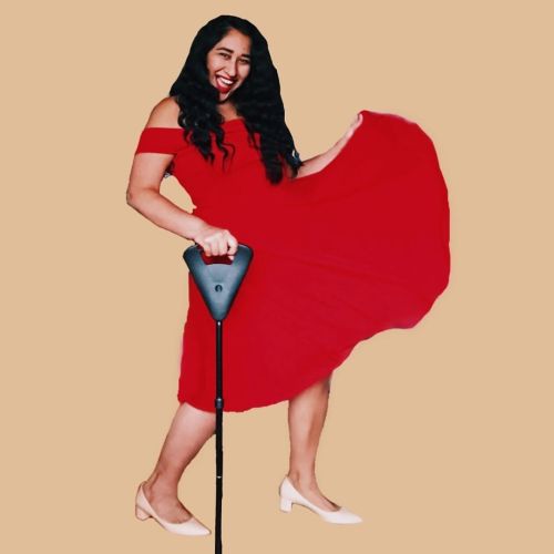 The Red Dress Dancing Emoji [Image Description: on a beige background, Annie stands with their cane,