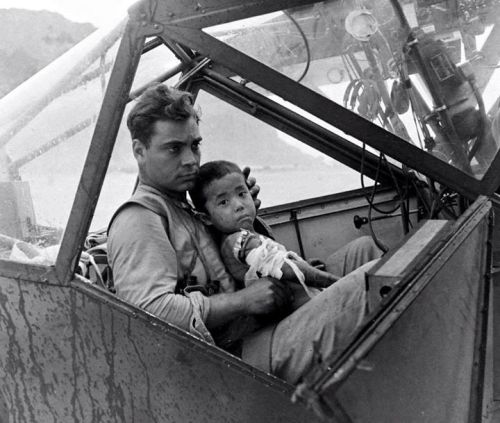 US soldier cradles a wounded Japanese boy in a cockpit during the Battle of Saipan, 1944. Photo by P