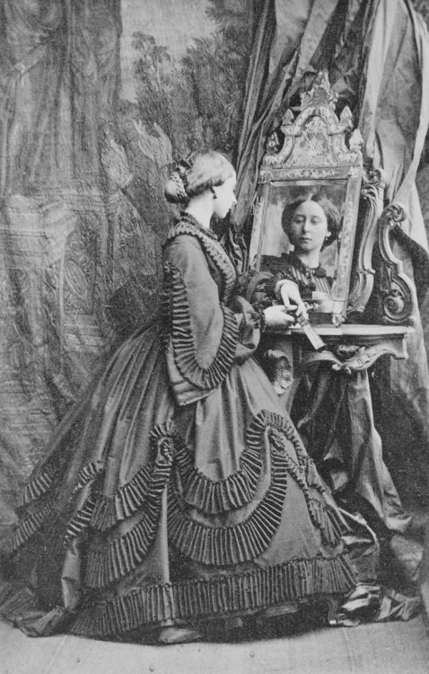 Princess Alice. 1861. Photograph of Princess Alice standing profile right, looking into a mirror tha
