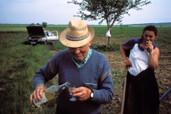 unrar:  As the landowner pours her a glass of slivovitz, a Serb refugee from Kosovo takes a break from corn harvesting in Yugoslavia, Ed Kashi. 