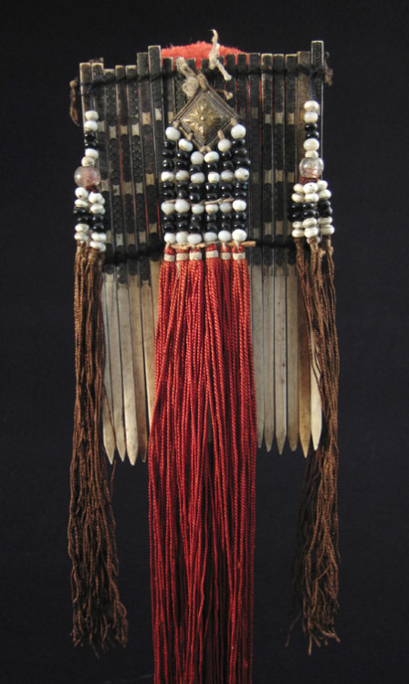 This is a colorful bone hair comb from Vietnam that stands 18.5” high. It has a red cotton pompom an