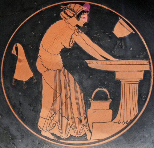 A woman at a washbasin, accompanied by a water bucket, a skyphos (two-handled wine-cup), and a wines