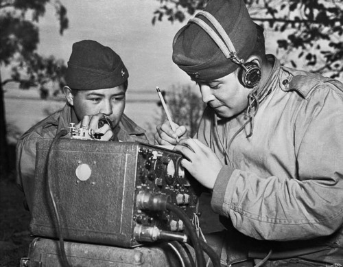 A two-man team of Navajo code talkers attached to a Marine regiment relay coded orders over a field 