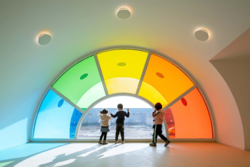 itscolossal:Hundreds of Rainbow Glass Panels Emit a Rotating Kaleidoscope in a Playful Kindergarten