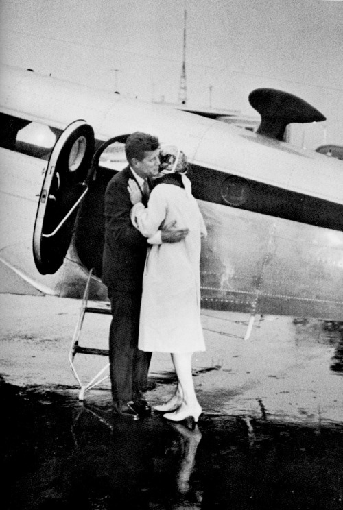 jfk-and-jackie:  John F. Kennedy standing in the rain at the airport embracing his wife in front of 