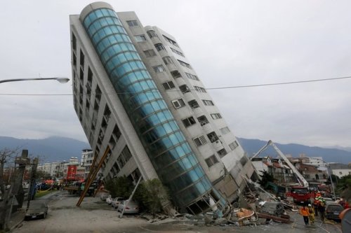 peterfromtexas:Rescue workers gather outside a building leaning at a precarious angle after an earth