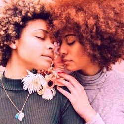 nothingrhymeswithchristmas:  [image desc:(1) two black people, both of whom have afros. one has blonde/dark brown hair and it wearing a grey ribbed top and a necklace. the other has red hair and is wearing a purple top. the two people’s faces are close