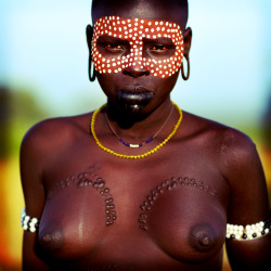 A Mursi girl, decorated with body paint and