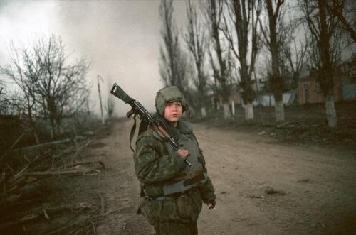 Chechnya. February, 2002.A Russian conscript stands guards while engineers clear mines from the area