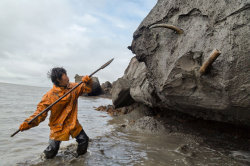 sixpenceee:    Slava Dolbaev uses a spear to dig out a corkscrewed tusk from a coastal ice cliff. Prying loose a single tusk can take hours, even days. Tusk hunters often leave colored beads or silver jewelry as offerings to local spirits.    Photograph