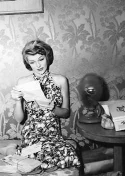 Rita Hayworth reads fan mail on the set of