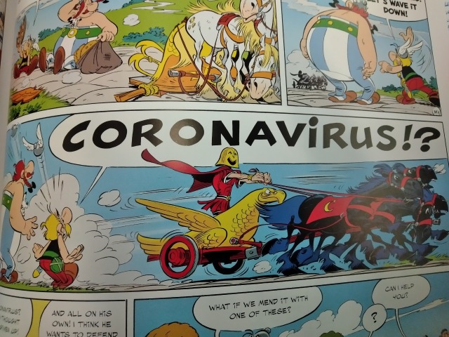 A panel from an Asterix comic book. A man in a chariot zooms past Asterix and Obelix, who yell "CORONAVIRUS?!" 