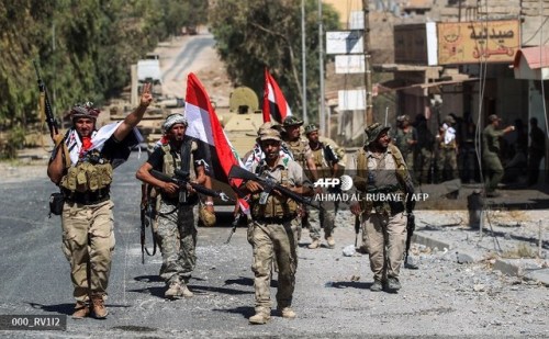 Fighters of the Hashed Al-Shaabi (Popular Mobilization units) advance through a street in the town o