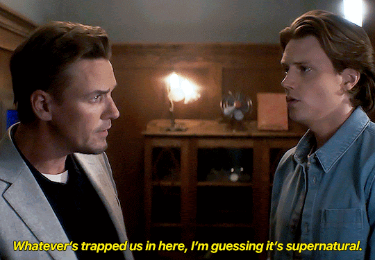 GIF FROM EPISODE 3X08 OF NANCY DREW. ACE AND RYAN ARE STANDING IN THE ARCHIVE ROOM OF THE HISTORICAL SOCIETY, IN FRONT OF THE CLOSED DOOR. ACE SAYS "WHATEVER'S TAPPED US IN HERE, I'M GUESSING IT'S SUPERNATURAL."