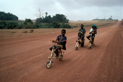 Boys ride bicycles on a country road near Booue. © Bruno Barbey 