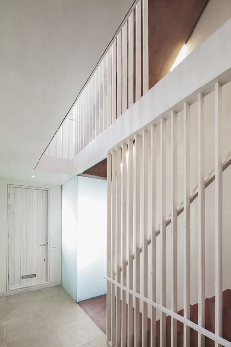 dezeen:     Latticed wooden screens form balustrades for a red pigmented concrete staircase inside t