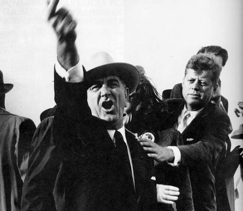 President John F. Kennedy prepares to restrain Vice President Lyndon Johnson, who is responding to a