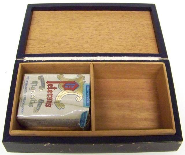 The interior of the box is lined with unstained wood and has two compartments, one with a pack of Peterson's Cigarettes.