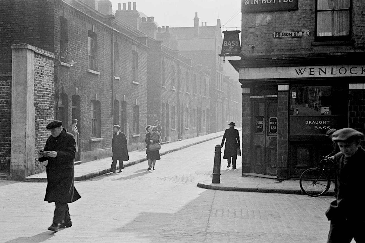 Bert Hardy. A view of pedestrians and a street corner pub in Prusom Street, Wapping, east London, 1949.
