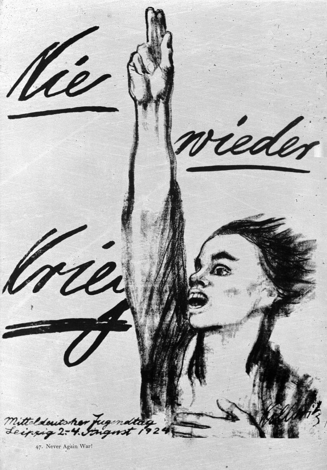 Black and white image of a figure showing one arm up straight up with two fingers pointing to the sky, other hand resting on the chest. The figure looks androgynous and the mouth is open as if to say “Never again war!” as written in German in the background.