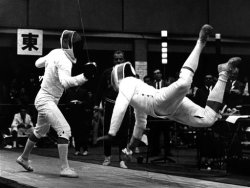 modernfencing:  [ID: two sabre fencers in a bout. The fencer on the right is falling forward, completely off the ground.] Jerzy Palowski (left) against Walter Kostner at the 1964 Olympics! 