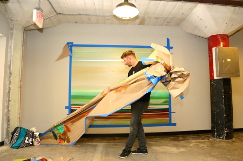 Artist Micah Crandall-Bear removes tape and paper to reveal his mural at Sacramento’s Warehouse Arti