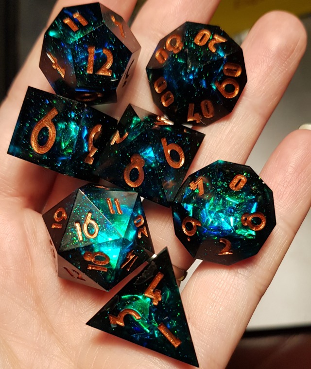 lesbeauan: vorchagirl:  Call of Cthulhu by Dicey Dungeons   [Image Descriptions: Two photos of a seven piece set of RPG dice resting on a person’s hand. The set is deep black, the center of each die swirled with a bright and vibrant blue and green galaxy