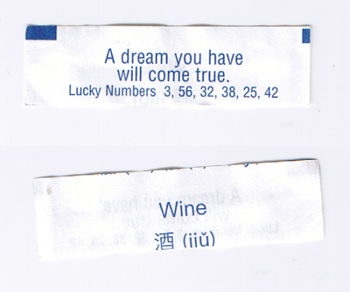 [A White Fortune Cookie Paper With Blue Text. Front: A Dream You Have Will Come True. Lucky Numbers 3,