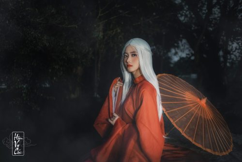 A fantasy photoshoot of a white-haired woman wearing Nguyễn dynasty red áo tấc, reminiscent o