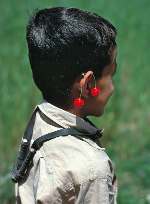 hopeful-melancholy:A young boy carries his slingshot around his neck and wears cherries like earring
