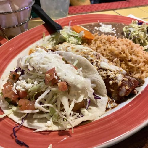 Fish taco and chicken adobada enchilada combo plate with rice, refried beans, spiced mango slaw.Sa