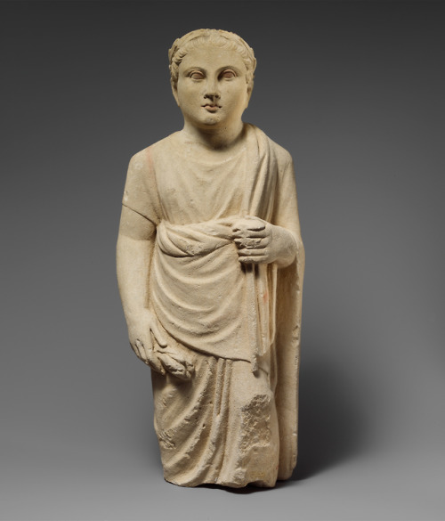 Ancient Greek limestone statuette of a young male votary holding a pyxis (cylindrical vessel with li