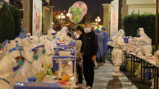 Medical personnel test visitors for the coronavirus at Shanghai Disneyland on Sunday after a single COVID-19 case was detected at the amusement park over the weekend.