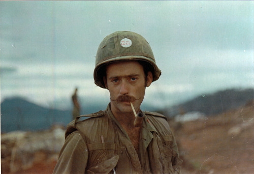 vietnamwarera:12th Inf. Reg. soldier wearing a flak vest and a pin on his helmet that reads, “We try