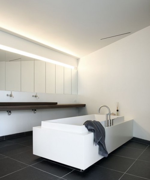 {This mostly white house is literally grounded by the dark floors. These darker elements also tend t