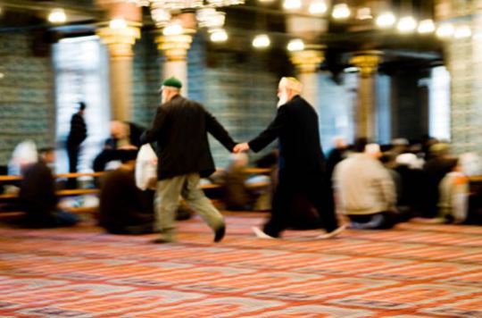 Two old men hand in hand rush for taking place for prayer time in the Yeni Cami mosque in Istanbul. Photographer: Marco Vacca