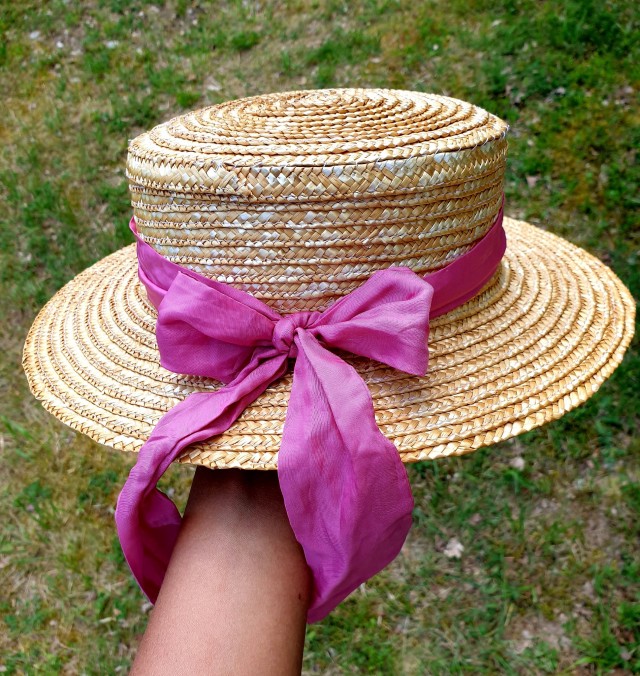 the back of the straw hat with the pink ribbon tied in a bow with the ends trailing 