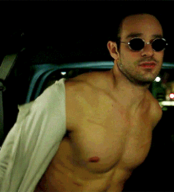 Matt Murdock taking off his white blouse shirt in the back of a car, smirking while he's doing so