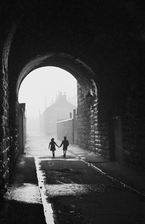 m3zzaluna:  gorbals children a boy and a girl hold hands under an archway in the gorbals,