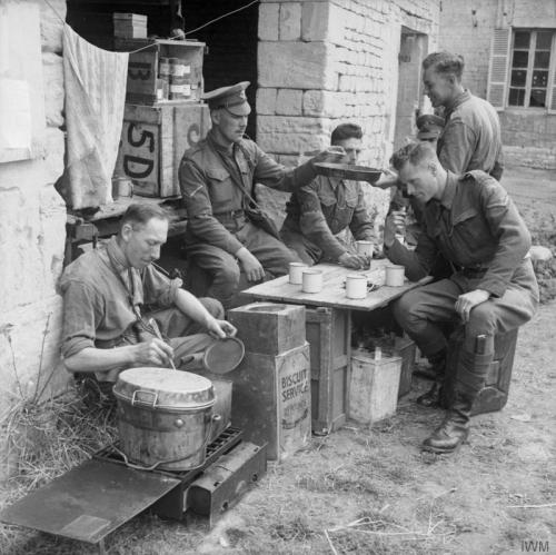 © IWM (B 6773) Military policemen, red-caps of 8th Corps eat their breakfast at Cully, 9 July 1