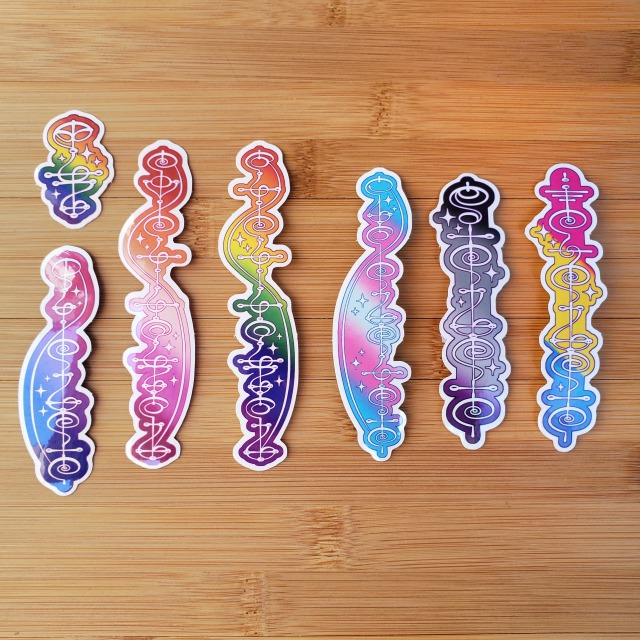 A selection of Vulcan Script Vinyl stickers with different sexualities written in Vulcan. Top left: "Pride" (yau) on rainbow colors From Left to right: "Bisexual" (duh-guvik) on pink, purple, blue "Lesbian" (ko-ka-ashausu) on orange, white, pink, rose "Gay" (sa-ka-ashausu) on rainbow colors "Transgender" (tuhs-guvanik) on blue, pink, white "Asexual" (riguvik) on black, grey, white, purple "Pansexual" (ek'guvik) on pink, yellow, blue