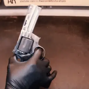 a person spinning a gun around in their glove-covered hand