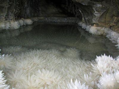 A photograph of a half-submerged cave with various crystal formations