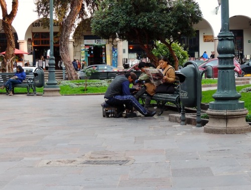 Plaza Recojico con hombre lustrabotas y una mujer leyendo periódico, Cuzco, 2017.
